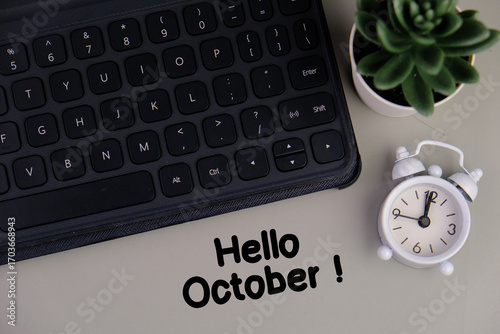 Monthly desk calendar for october 2024 year on wooden table with  alarm clock.