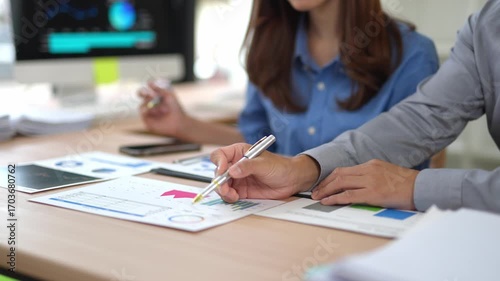 Professional business team analyzing financial performance, reviewing data driven charts and graphs while collaborating on strategic planning in modern corporate office setting