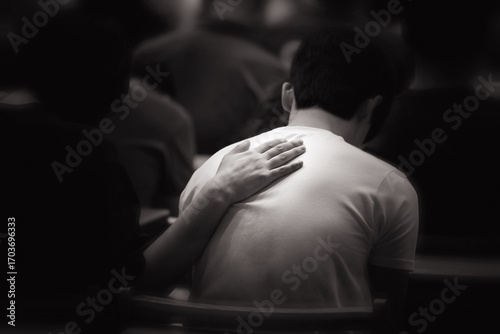 A Christian who places his hands on the backs of people in despair during prayer time, comforts them, and prays with tears in his eyes.
