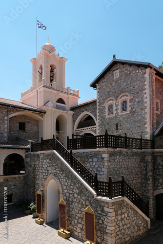 Greek flag above the bell tower of Holy Monastery of the Virgin Mary of Kykkos on sunny summer day. Cyprus.