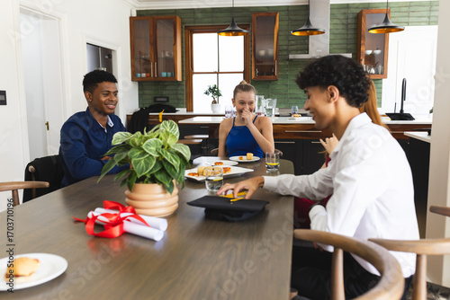 Teens celebrating graduation at home, enjoying food and laughter around table