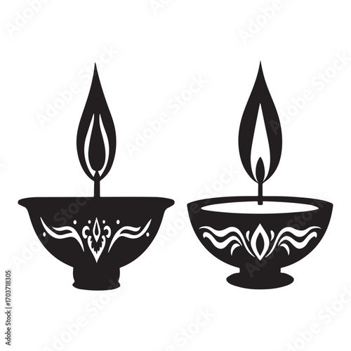 This is a simple, black and white illustration of two decorative oil lamps, likely diyas. They each have a flared rim and ornate patterns, with a flame rising from a wick. The lamps are silhouetted 
