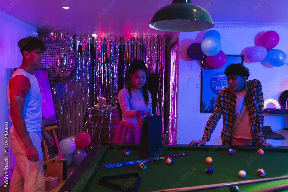 Obraz premium Teens enjoying pool game at vibrant party with colorful balloons and decorations