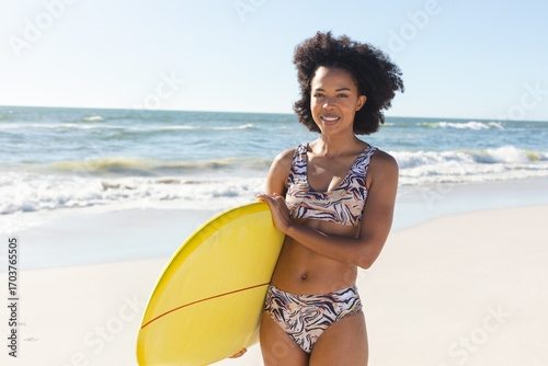 Smiling woman holding surfboard on sunny beach, enjoying summer day, copy space