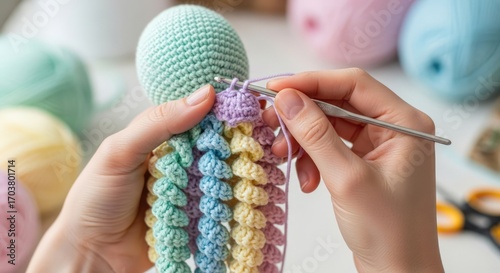 Close-up of hands crocheting a colorful octopus toy with yarn and a crochet hook.