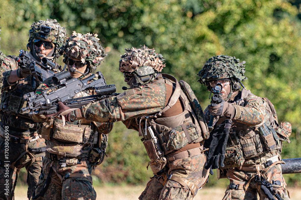 Fototapeta premium German Bundeswehr paratroopers in a NATO exercise assist an injured comrade, symbolizing teamwork, training, and military readiness.