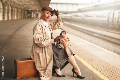 Elegant woman in vintage attire enjoys the ambiance of a train station during the day while waiting for her journey to begin