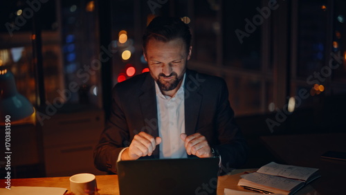 Frustrated executive reacting failure at desk night. Mad employee hitting table