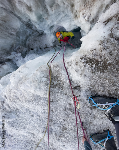 Quadro su tela Climber in vibrant colors belaying from glacier crevasse during rescuing action, extreme sports enthusiasts, high-altitude mountaineering, adventure, outdoor, extreme activity concept