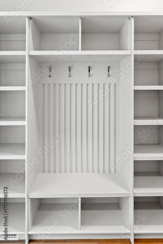 White closet with a bench and a rack for hanging coats