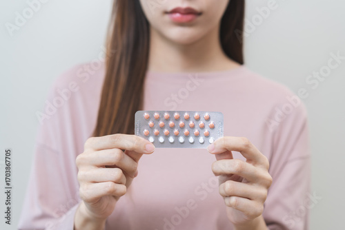 Contraception and pregnancy, menstruation concept, birth control pills asian young woman hand holding hormonal oral contraceptive medicine, take pharmaceutical to prevention, safe virus sex disease.