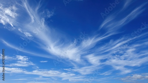 Wispy clouds drift gracefully across a vibrant blue sky during a bright sunny day, creating a peaceful atmosphere perfect for outdoor activities and relaxation.