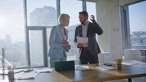 Two colleagues looking documents discussing budget in modern office closeup