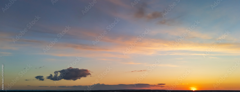Fototapeta premium Breathtaking sunset skyline showcasing vibrant orange and purple hues. A single cloud drifts lazily across the horizon, creating a peaceful atmosphere.