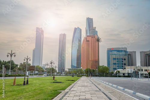 Abu Dhabi, UAE – August 16, 2025: Skyscrapers overlook a palm-filled park with fountains at sunset in the capital of the United Arab Emirates.