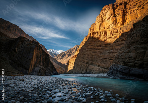 A breathtaking view of a zanskar river flowing through a narrow gorge, with steep, rocky canyon walls under a blue sky.