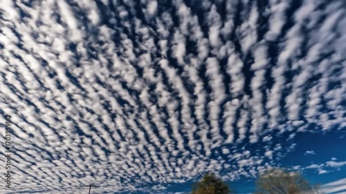 A dense, textured sky of small, puffy clouds arranged in patterned rows against a deep blue backdrop