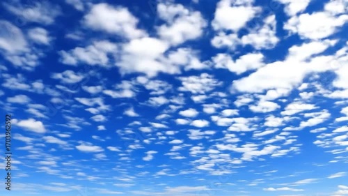 A vast expanse of a vibrant blue sky dotted with scattered, puffy white clouds