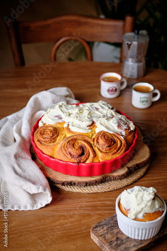 Cinnabon cinnamon rolls with pumpkin, nuts, caramel and mascarpone cream, covered with glaze. Rustic wooden table. Side view. Sweet homemade pastries, autumn pastries.