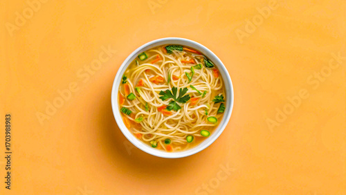 Bowl of noodle soup with vegetables on orange table