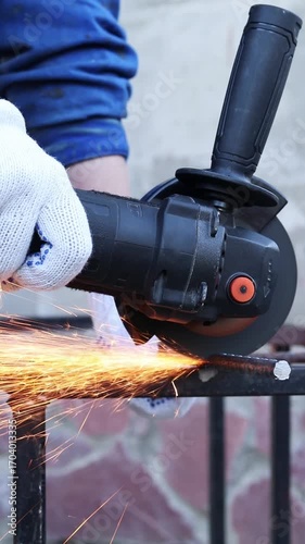 Close-up of an angle grinder cutting rebar. Female hands in work gloves holding a cordless grinder and cutting rebar into small pieces. Power tool for construction and repair work