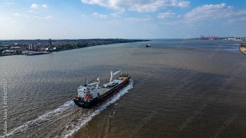 Fototapeta premium Cargo ship on water with coastal city and port in Liverpool, UK.