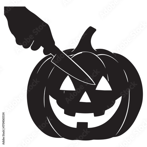 Silhouette of a hand carving a spooky jack o lantern with a knife for halloween