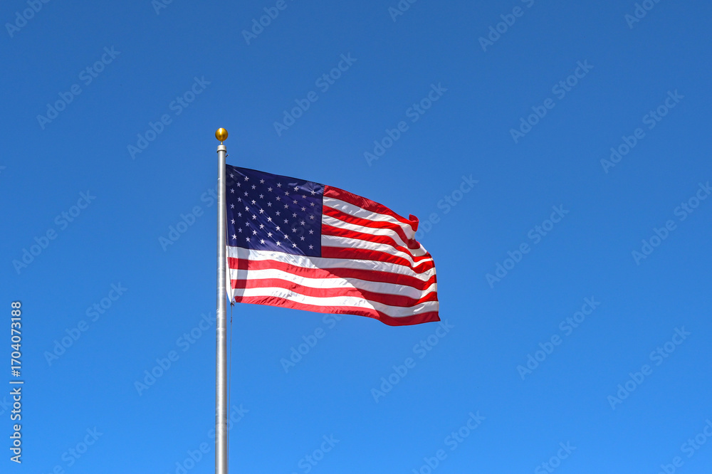 Fototapeta premium United States of America national flag The Stars and Stripes, isolated against a deep blue sky. Copy space. No people.