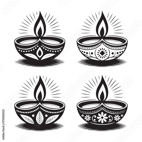 Four decorative black and white diya oil lamps with flames