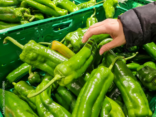 A woman buying while piping, a hand picking a green pepper