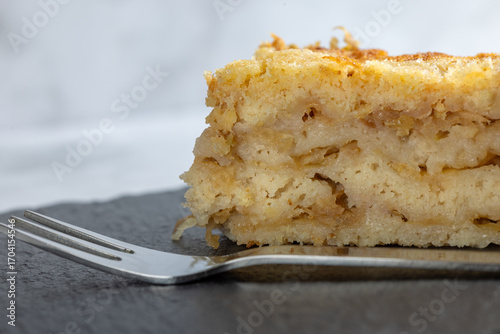 Moist layered apple semolina pie with crispy golden topping and fork.