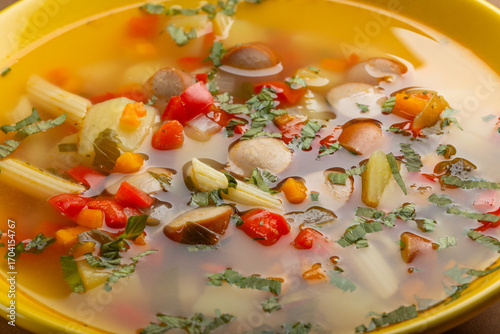 Delicious homemade soup with sausages, colorful peppers and fresh herbs