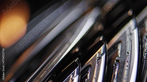 Close-up sequence of gleaming metallic surfaces reflecting light, showcasing intricate details and textures, capturing the dynamic interplay of light and shadow in a continuous motion flow