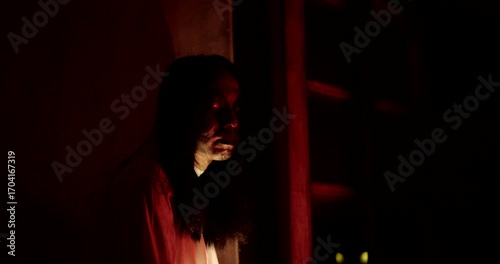 Horror scene of a person Mysterious Figure Asian ghost woman creepy have long hair looking to camera in Nighttime Scene with Eerie Red Light, festival Halloween