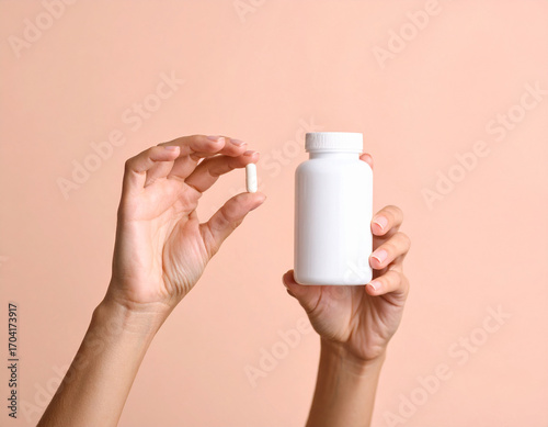 Hands Holding White Pill and Bottle on Peach Background - Healthcare and Wellness