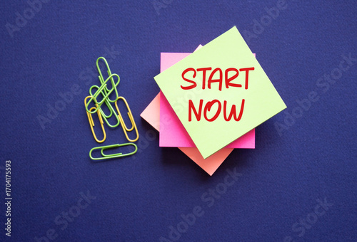 Start now symbol. Yellow sticky note with words Start Now. Beautiful deep blue background. Business and Start now concept. Copy space.