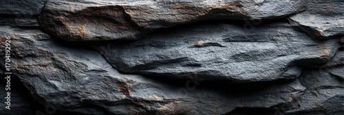 Textured dark rock surface from a natural formation showcasing unique patterns and colors in natural light