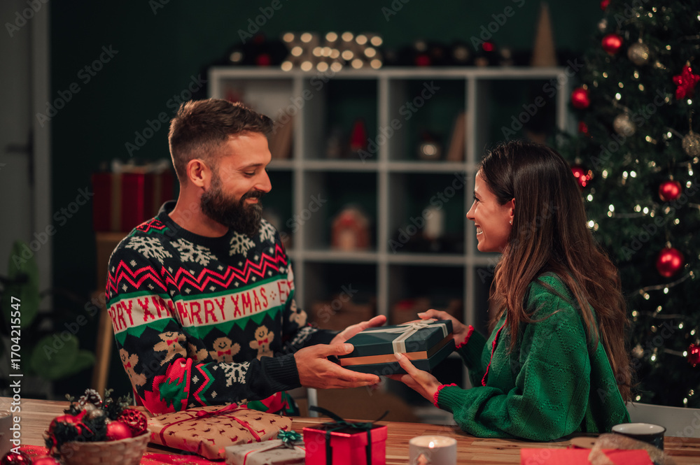 Fototapeta premium Couple exchanging christmas gifts at home
