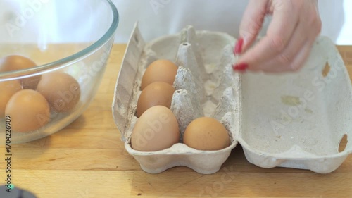 Person is holding an egg in a carton. There are six eggs in the carton