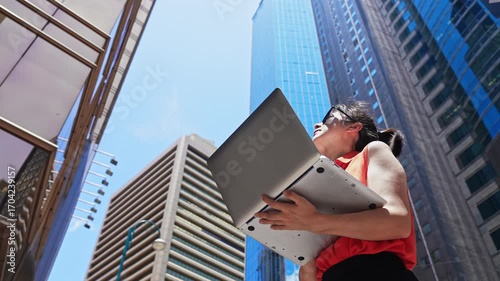 Businesswoman using laptop outside the office building in HONG KONG