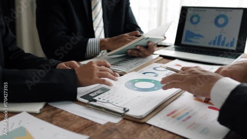 Corporate team reviewing financial charts, analyzing market trends, strategizing investment approaches in modern conference room setting