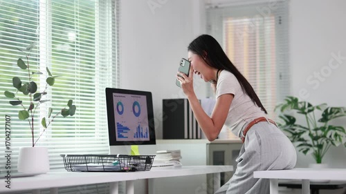 Successful businesswoman cheering, receiving great news while typing on laptop, showing genuine joy in contemporary workplace environment