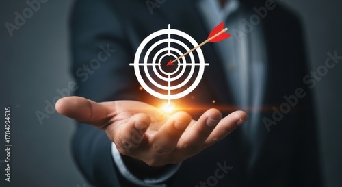 Businessman holding a target with an arrow in the center, symbolizing success and achievement