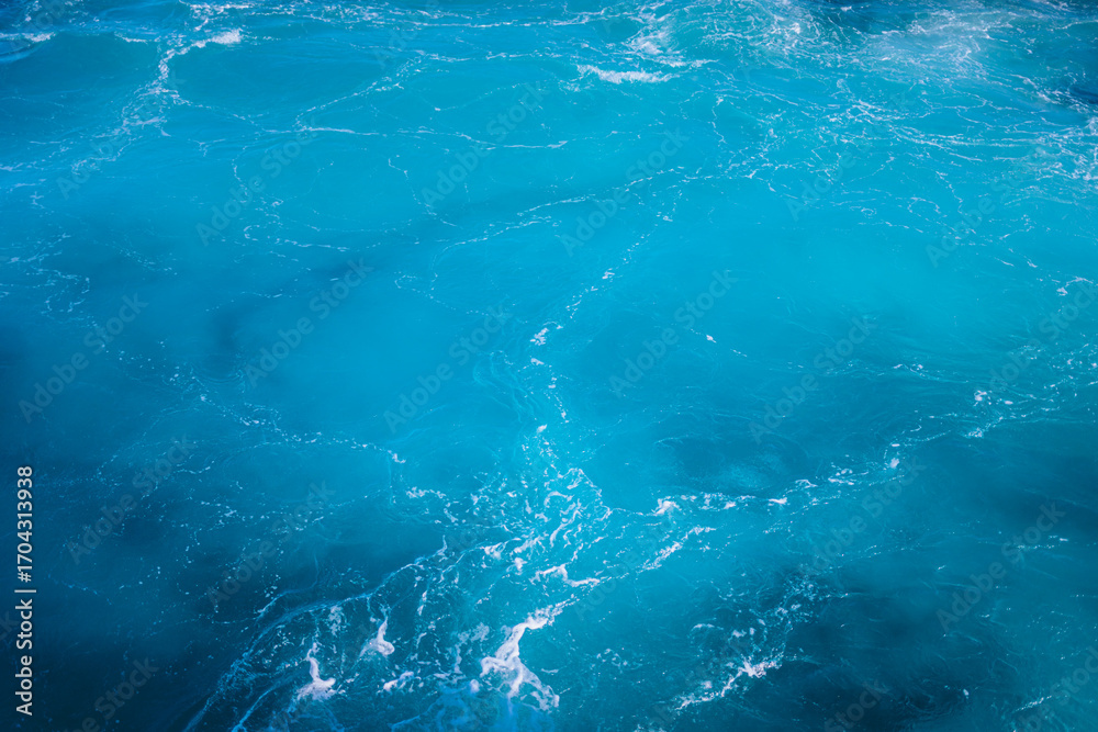 Obraz premium Vibrant turquoise ocean waves gently lapping against the shoreline under bright sunlight during midday