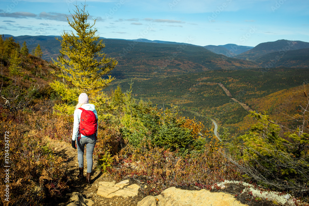 Obraz premium Hiker explores a scenic mountain trail during autumn in a vibrant landscape in daylight