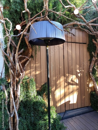 Beautiful design (interior) with shrubs, a tall lamp, and natural tree trunks