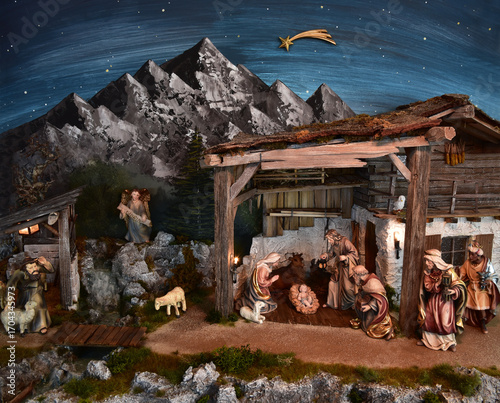 Weihnachtskrippe im alpenländischen, ländlichen Stil, mit Bergen und Nachthimmel als Hintergrund, in gemütlichem Stall aus alten Holzbalken und stimmungsvoller Beleuchtung