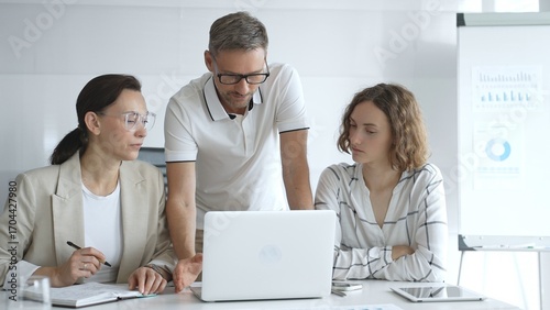 Business team collaborating and analyzing data on a laptop during a dynamic office meeting, uniting efforts to reach shared objectives and drive successful outcomes together