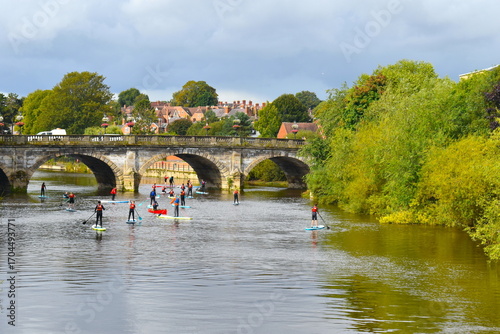 Paddle boarding is a popular outdoor activity between the English and the Welsh Bridges in the historical old town of Shrewsbury for tourists and locals of all ages during the summer school holidays.