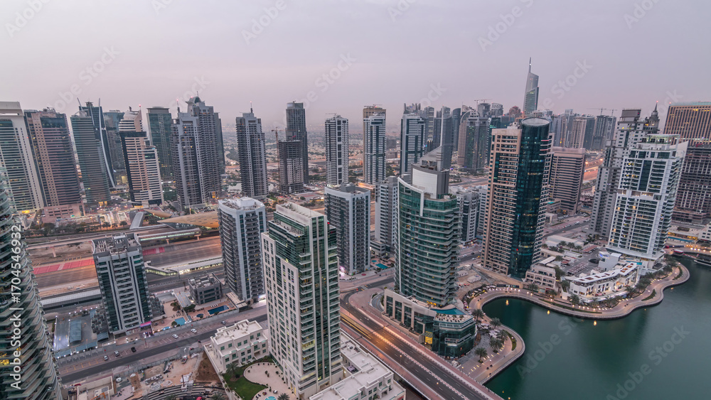 Obraz premium Aerial top view of Dubai Marina night to day timelapse. Modern towers and traffic on the road